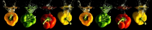 four several coloured paprika falling into water